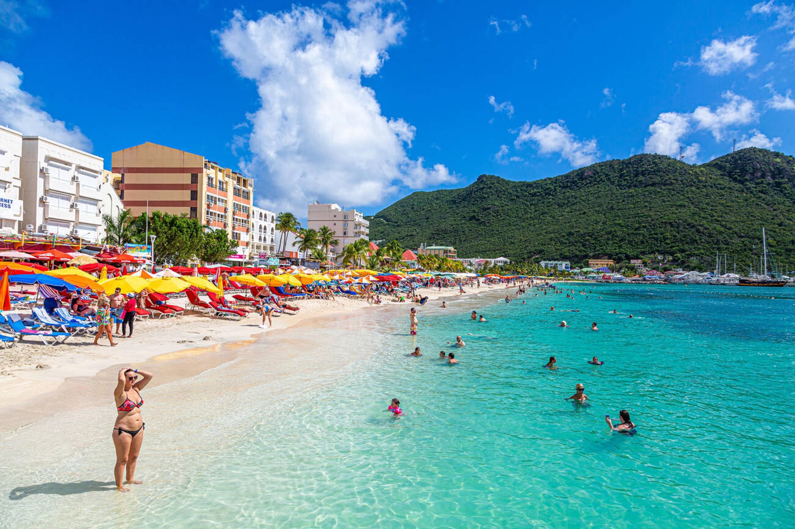 Beach view of St. Maarten with tourists enjoying the water, representing the All Day Tour exploring both Dutch and French sides.